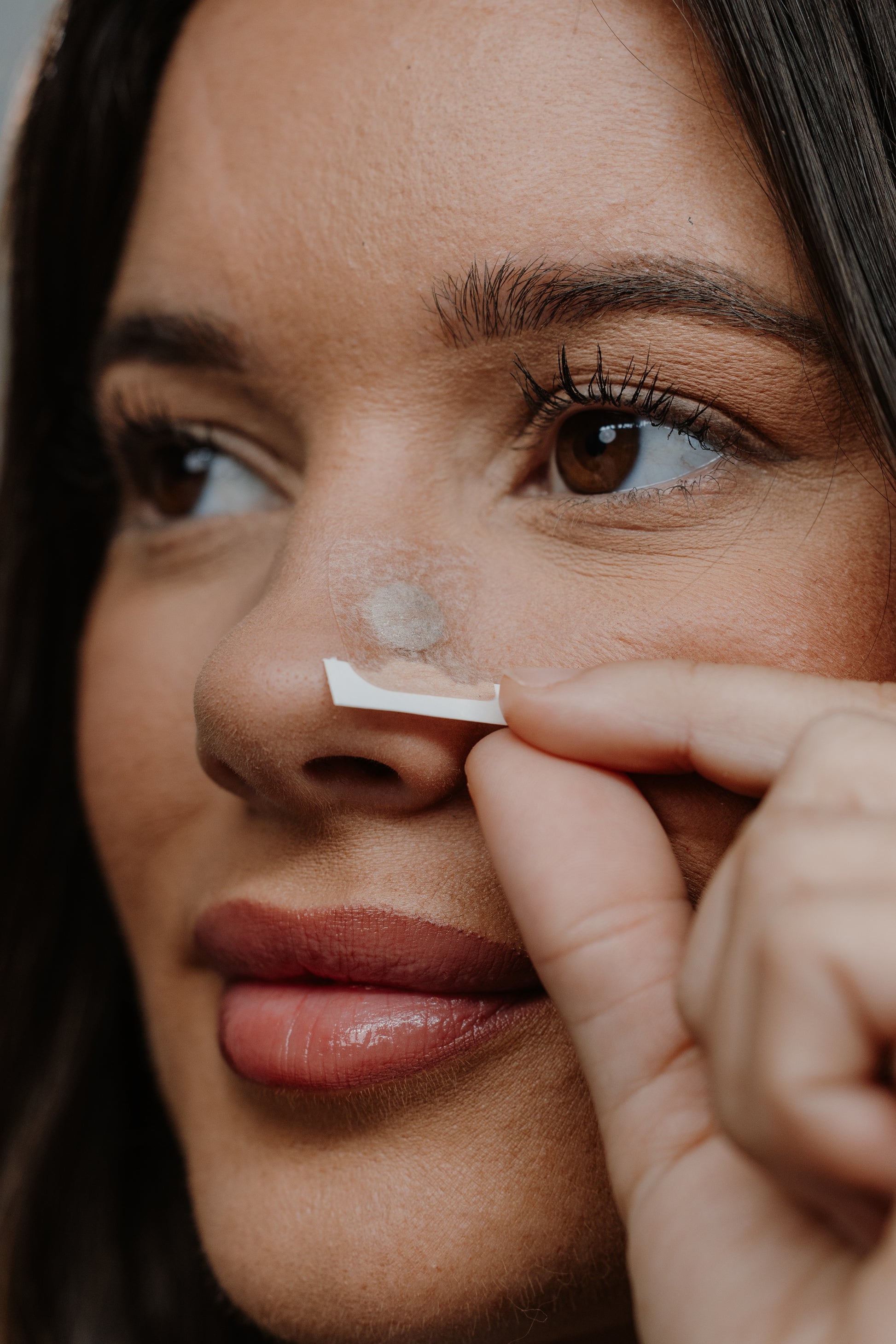 Close-up of a person applying a patch to their nose.